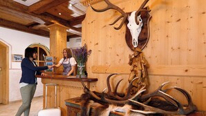 Un intérieur en bois, orné d’un crâne de cerf accroché au mur, avec un espace bar et un comptoir d’accueil.