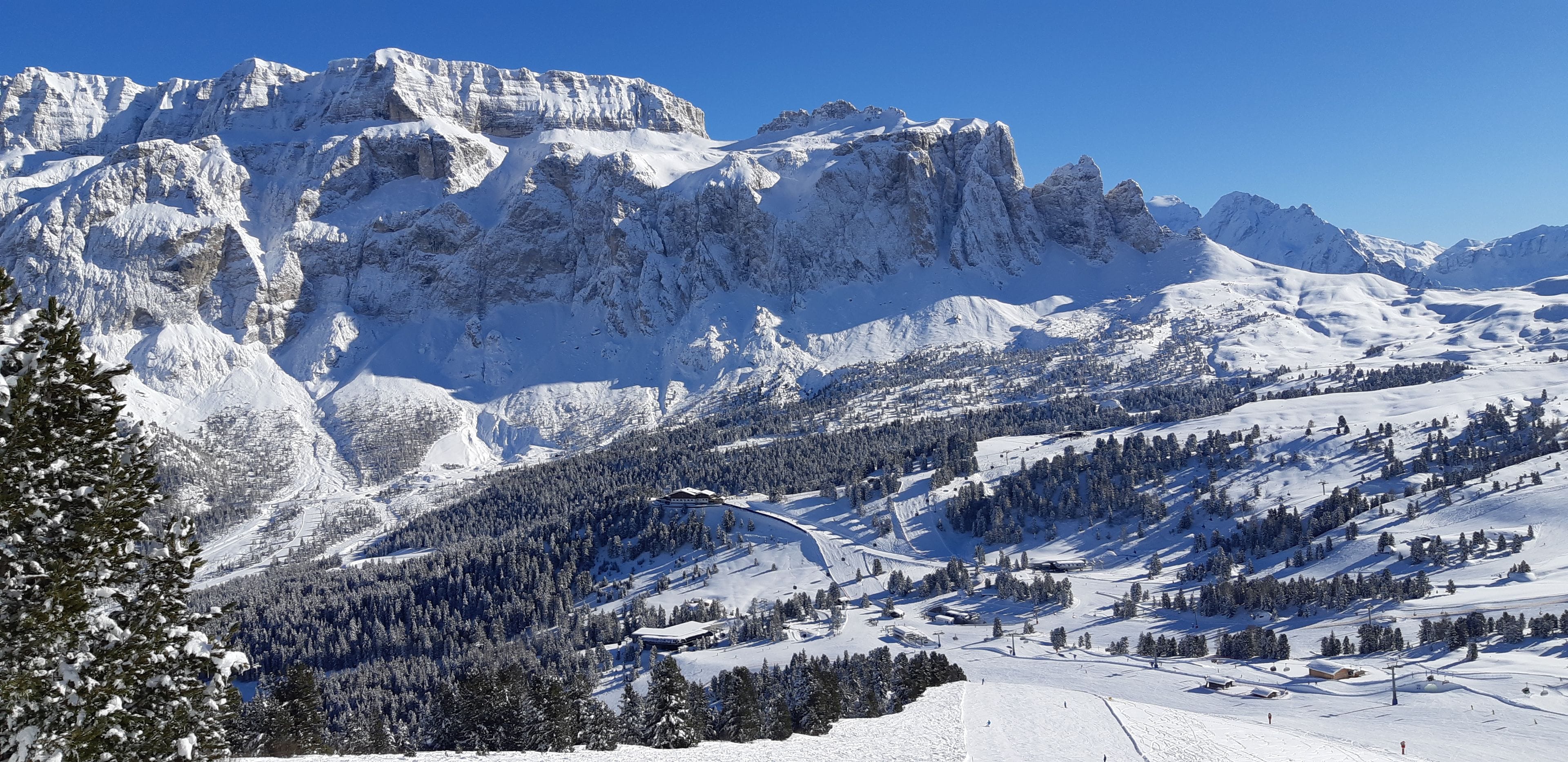 Eine verschneite Berglandschaft mit einem Skigebiet, einschließlich Skipisten und Gebäuden.