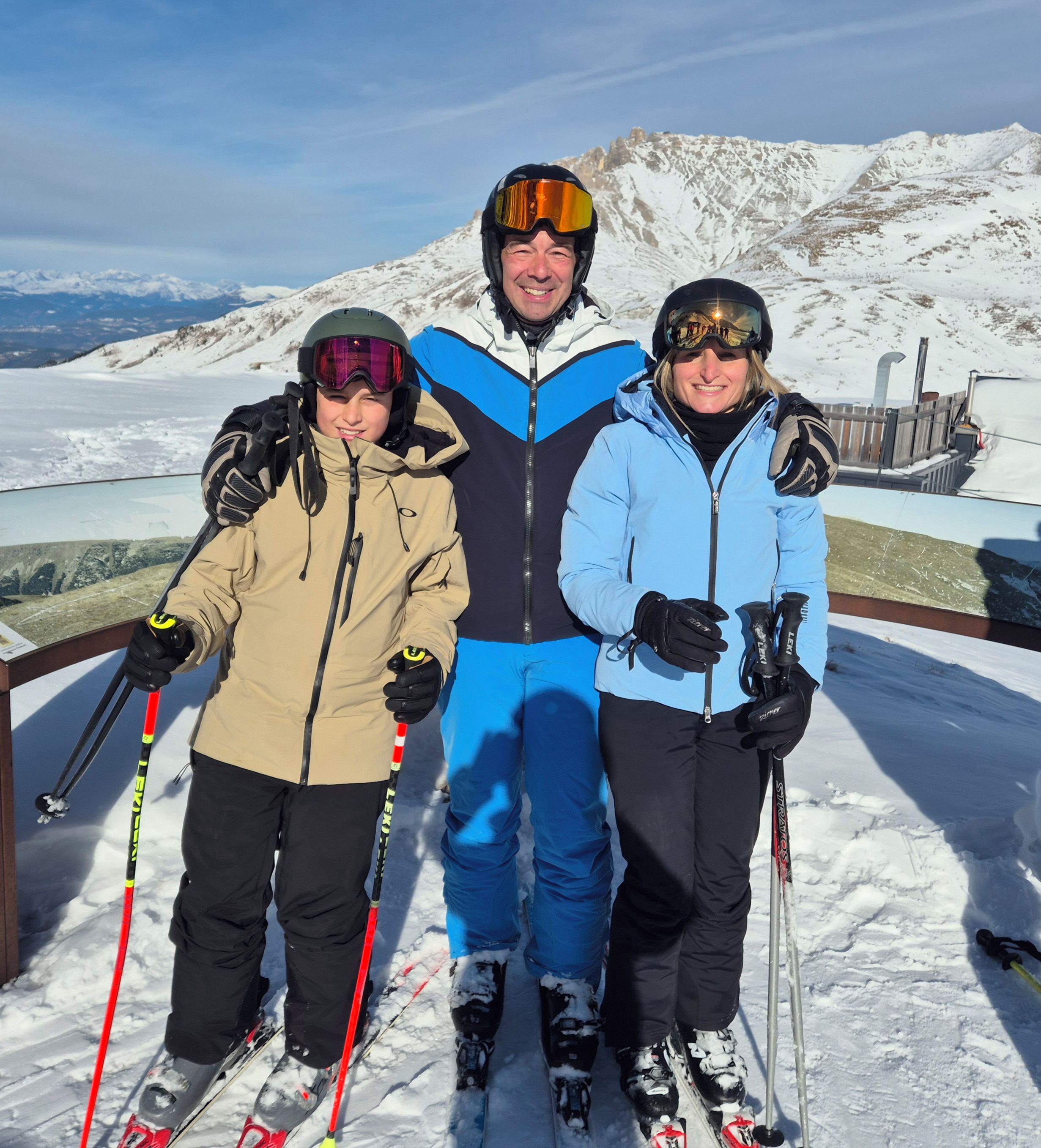 A group of people on a snowy slope with ski poles, wearing winter gear and helmets.