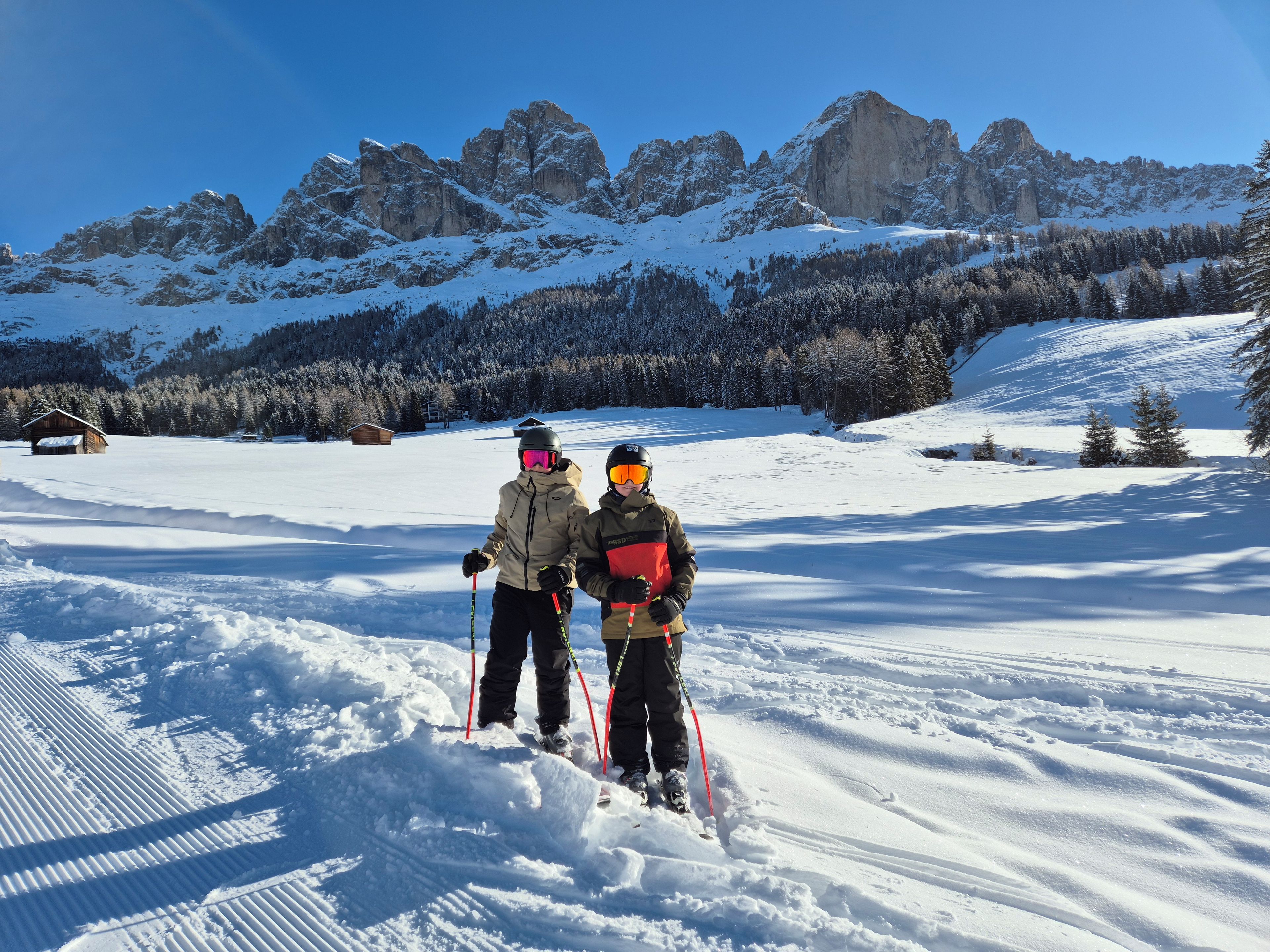 Two skiers on a snowy slope with a mountain backdrop.
