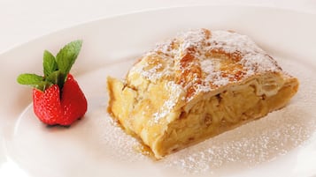 A slice of cake with powdered sugar and a strawberry on a white plate.
