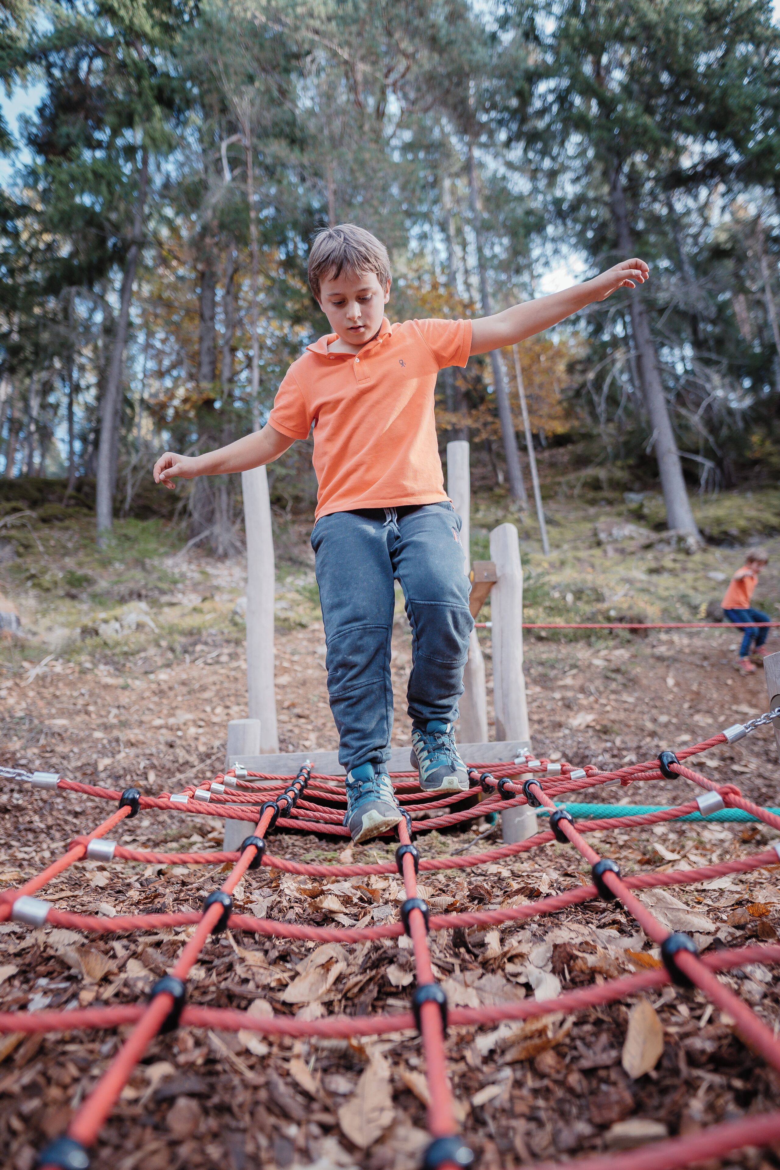 A person standing on a rope bridge in a wooded area.