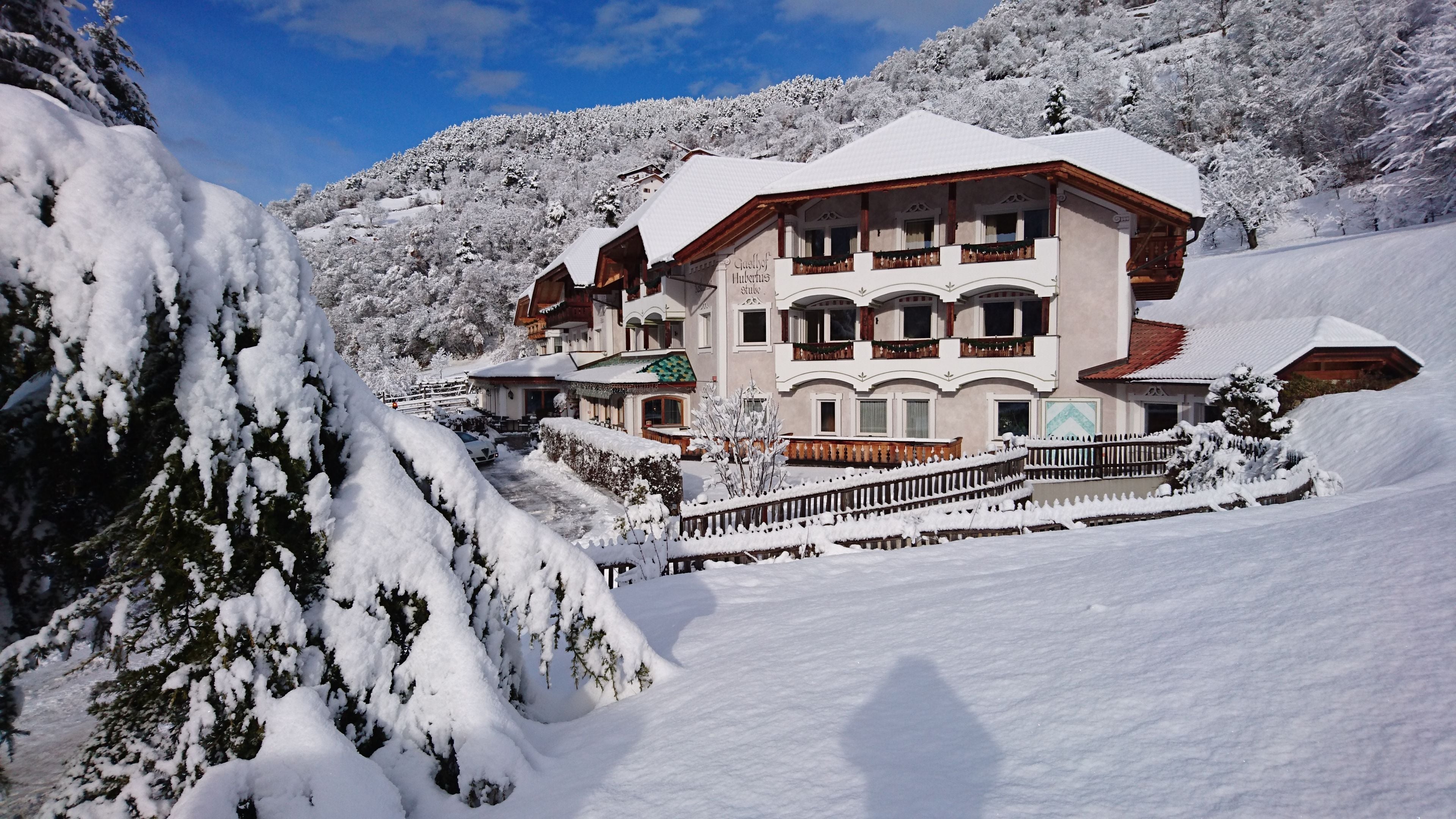 A multi-story hotel with a snow-covered roof and balconies, surrounded by a mountainous landscape.