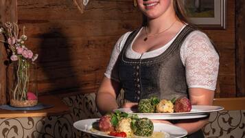 A person holding a plate with food, standing in a room with wooden walls and a deer skull decoration.