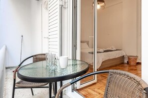 Cozy retreat with a glass dining table and wicker chairs, featuring a comfortable bed with a white duvet.