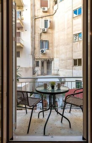 Enjoy the serene view from this Mediterranean-style balcony, featuring a round table and two wicker chairs.
