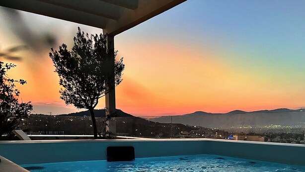 Una piscina con vista a una puesta de sol y montañas distantes.