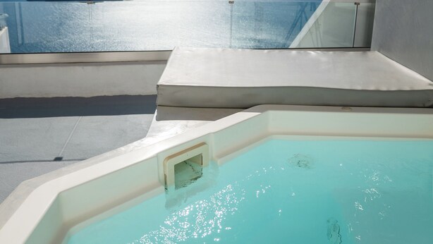 Una piscina con vista despejada al mar y montañas a lo lejos.