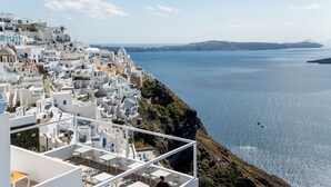 Un pueblo costero con edificios blancos, un mar azul cristalino y un acantilado rocoso.