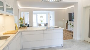 Una cucina moderna con mobili bianchi, un'isola centrale e una zona pranzo con tavolo e sedie.