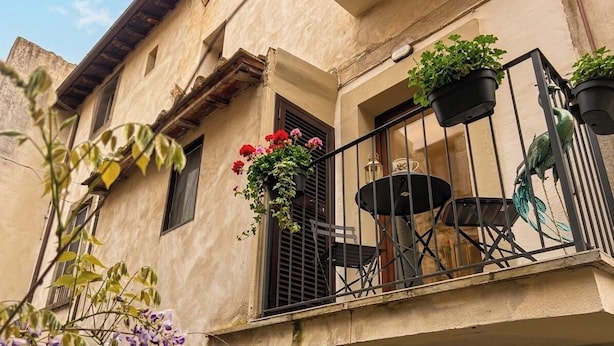 A balcony with potted plants, a table, and a chair. - Camera ampia matrimoniale/tripla (Vitorchiano)