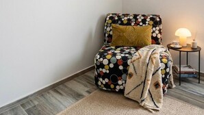 A corner room with a patterned ottoman, a lamp, and two framed artworks on the wall. - Camera ampia matrimoniale/tripla (Vitorchiano)