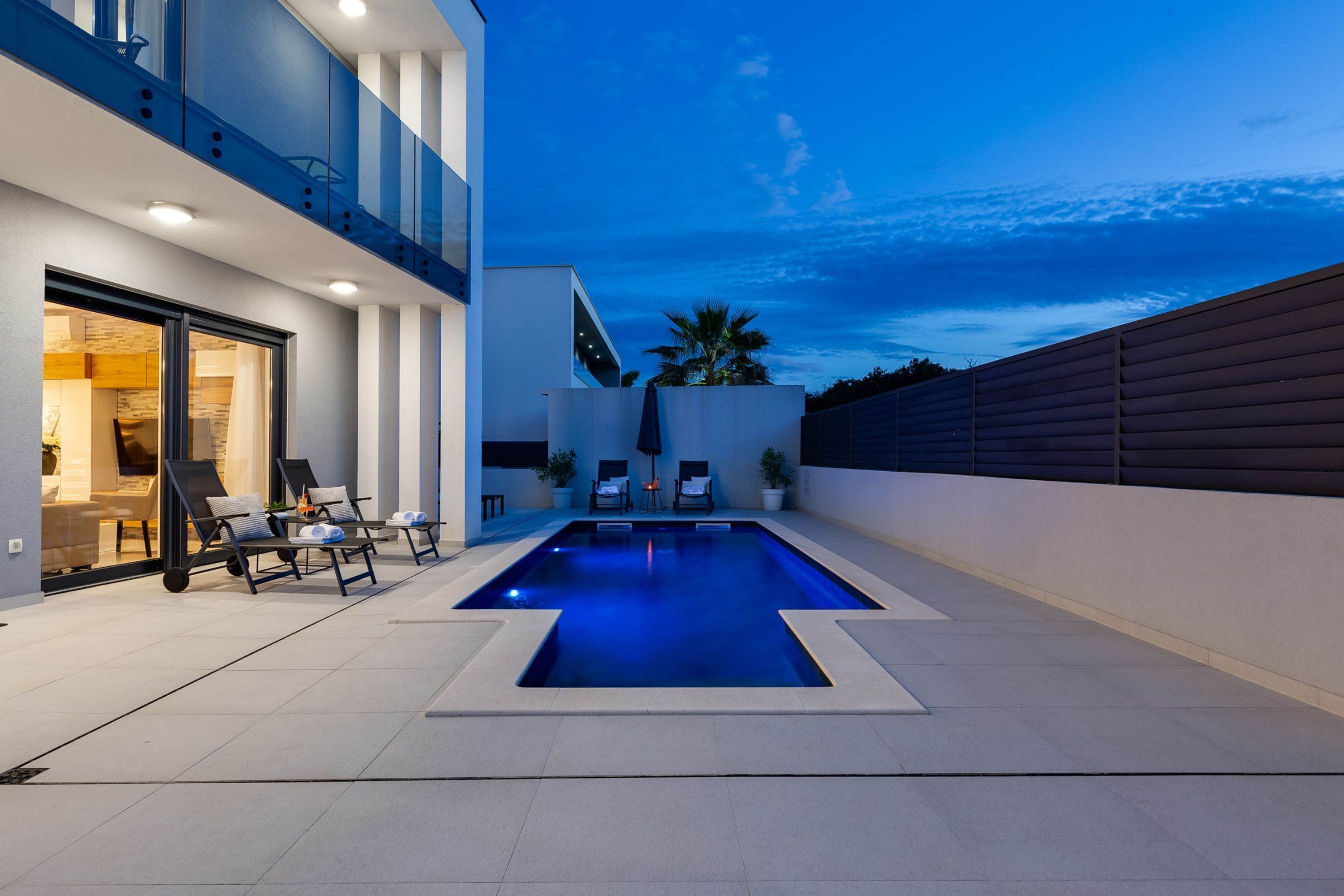 A modern outdoor swimming pool with lounge chairs and a view of the sky.