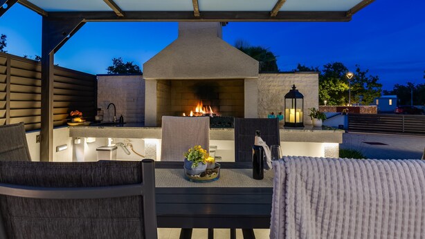 An outdoor patio with a built-in fire feature, seating, and a small table with a vase of flowers. - Villa Martina Zadarvillas (Nin)