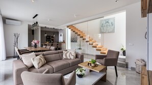 A modern living room with a large sectional sofa, a coffee table, and a staircase leading to an upper level. - Villa Martina Zadarvillas (Nin)