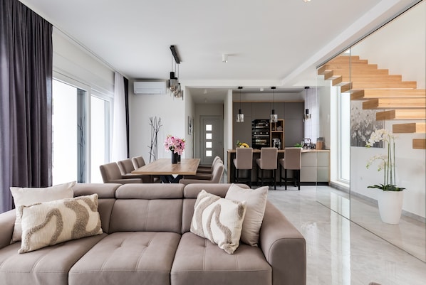 A modern living room with a sectional sofa, a dining area, and a kitchen in the background. - Villa Martina Zadarvillas (Nin)