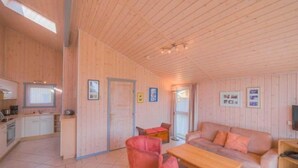 A wooden interior with a kitchen, dining area, and living room. - Ferienhaus in Rechlin (Rechlin)