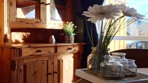 Ein Holzkabinent mit Glastüren, eine Vase mit weißen Blumen und die Zahl 28 auf einem Regal.