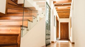 A wooden staircase with glass railings leading to a hallway with wooden beams on the ceiling. - Luxury Casa Guayllabamba - BBQ Jacuzzi Gym Piscina (Guayllabamba)