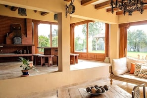 A spacious kitchen with a brick oven, wooden furniture, and large windows offering a view of the outdoors. - Luxury Casa Guayllabamba - BBQ Jacuzzi Gym Piscina (Guayllabamba)
