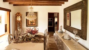 A dining area with a wooden ceiling, a chandelier, a large mirror, and a table set with a vase and glassware. - Luxury Casa Guayllabamba - BBQ Jacuzzi Gym Piscina (Guayllabamba)