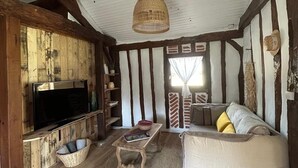 Un saló rústic amb bigues de fusta a la vista, una televisió, un sofà i una cistella teixida.