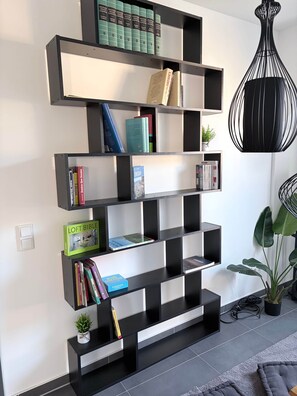 A modern bookshelf with multiple shelves, some with books and others empty. - Familien Suite in Elbflorenz (Dresden)