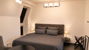 Une chambre à coucher avec un lit, deux lampes de chevet, une table ronde, une chaise et une petite table.