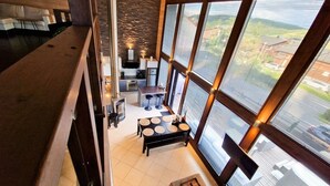 Un intérieur moderne comprenant une cuisine, un coin repas et de grandes fenêtres offrant une vue dégagée.