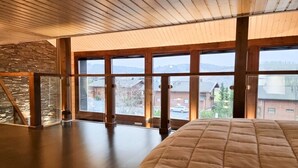 Une pièce spacieuse avec de grandes fenêtres, un mur en pierre et un plafond en bois.