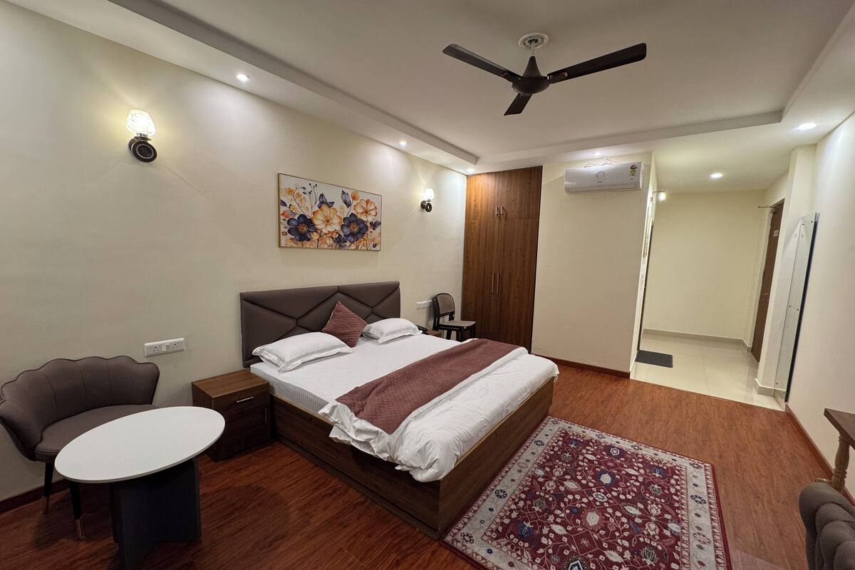 A modern bedroom with a large bed, a desk, a chair, a ceiling fan, and a decorative rug.