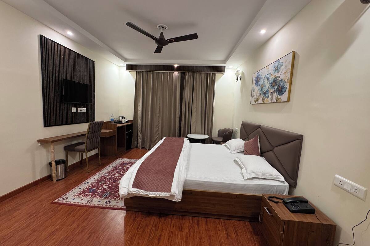 A hotel room with a bed, desk, chair, and a ceiling fan.