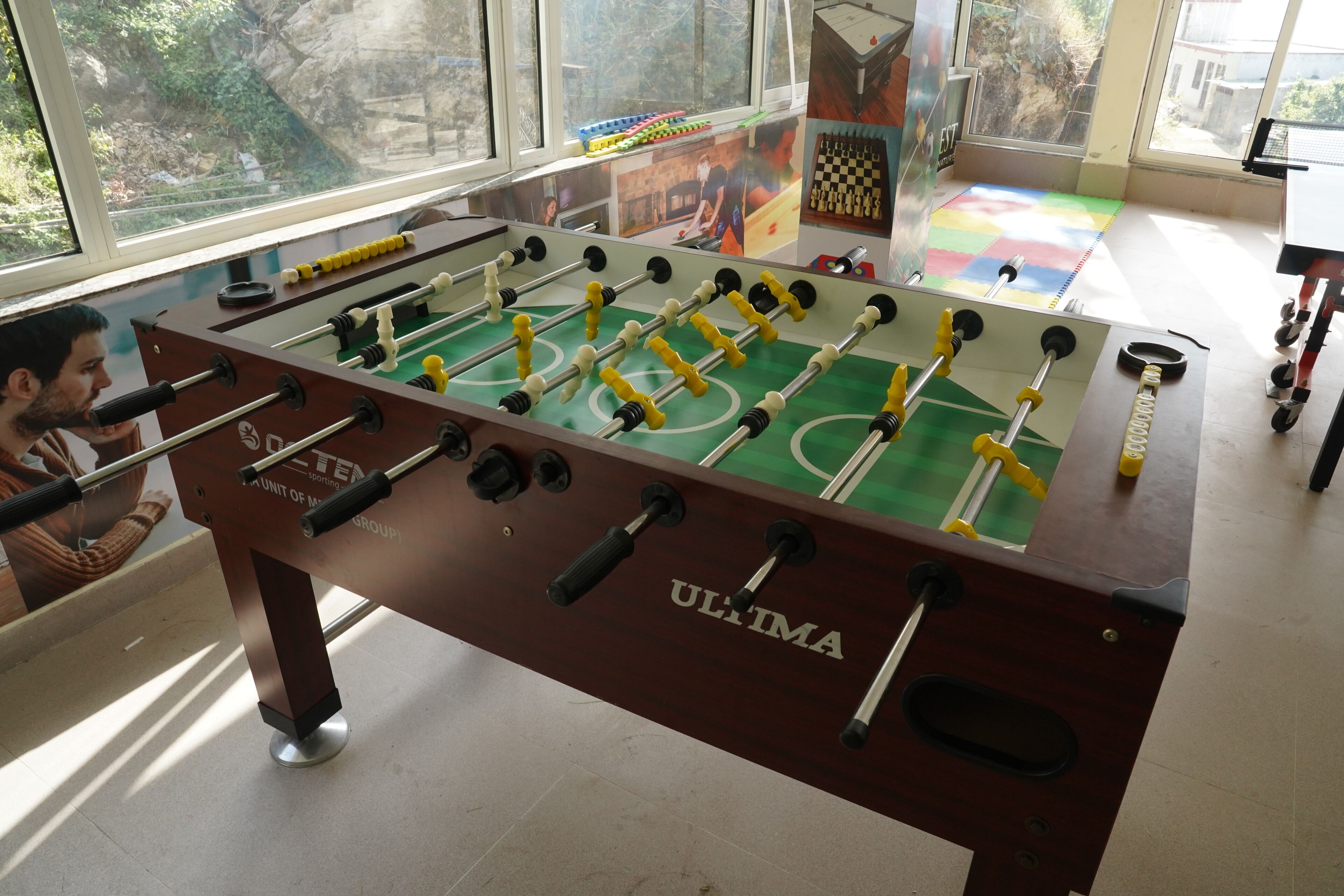 A foosball table with a green playing surface and yellow and white player figures.