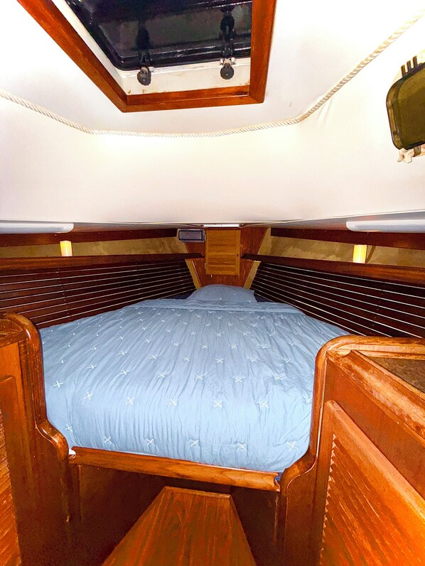A compact, single-bed RV with a wooden interior, a small window at the top, and a built-in storage compartment under the bed.