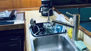 A compact kitchenette with a sink, a coffee maker, and two small windows. - Welcome to Your floating home-away-from-home: Calm, Cozy, and Unforgettable (Miami)