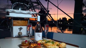 A table with a bottle of Tra Maxuri wine, two glasses, and a variety of pastries and fruits. - Welcome to Your floating home-away-from-home: Calm, Cozy, and Unforgettable (Miami)