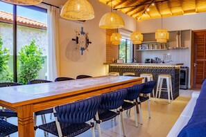 Eine moderne Küche mit Holztisch und -stühlen, einer Bar und Blick ins Grüne.