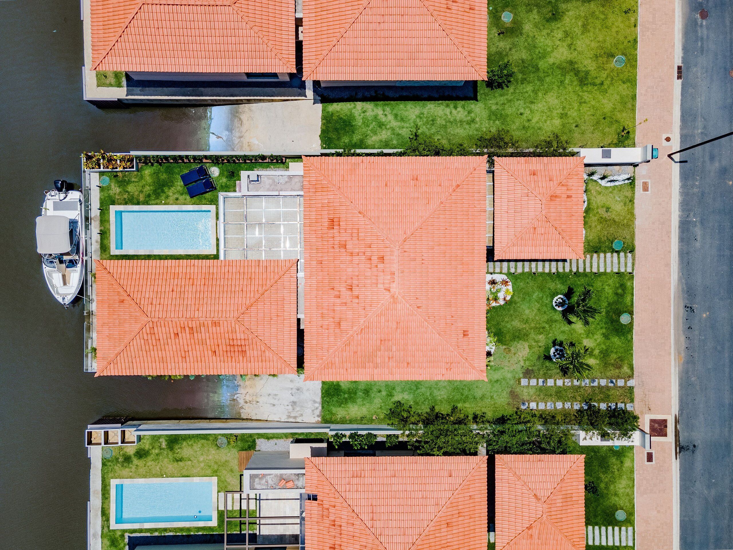 Vista aérea de una zona residencial con varias casas, una piscina y un muelle para barcos.