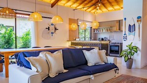 Una cocina moderna con comedor, un sofá con cojines y una planta en maceta.