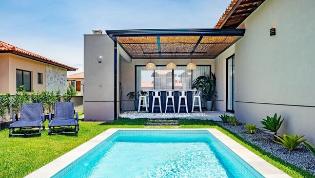 Una piscina con pérgola y sillas de descanso.