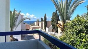 A balcony with a view of a coastal area, featuring palm trees and buildings. - Family Design Villa & Play Garden near Sea, 3 BR, Sea Views (Chlorakas)