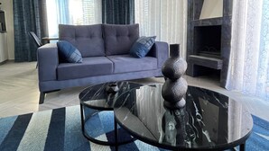 A modern living room with a grey sofa, a glass coffee table, and a fireplace. - Family Design Villa & Play Garden near Sea, 3 BR, Sea Views (Chlorakas)