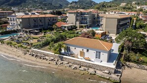 A coastal hotel with multiple buildings, a swimming pool, and a beach.