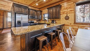 A spacious kitchen with wooden cabinets, a granite countertop, and a large island with stools.