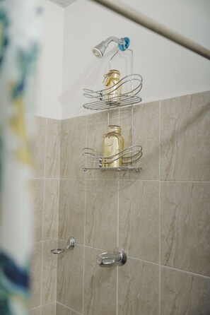 A bathroom with a shower, a towel rack, and a soap dispenser on a shelf. - Hotel D Palace (Dhaka)