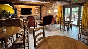 Un intérieur rustique avec des murs en pierre, des meubles en bois, un téléviseur et un coin repas.