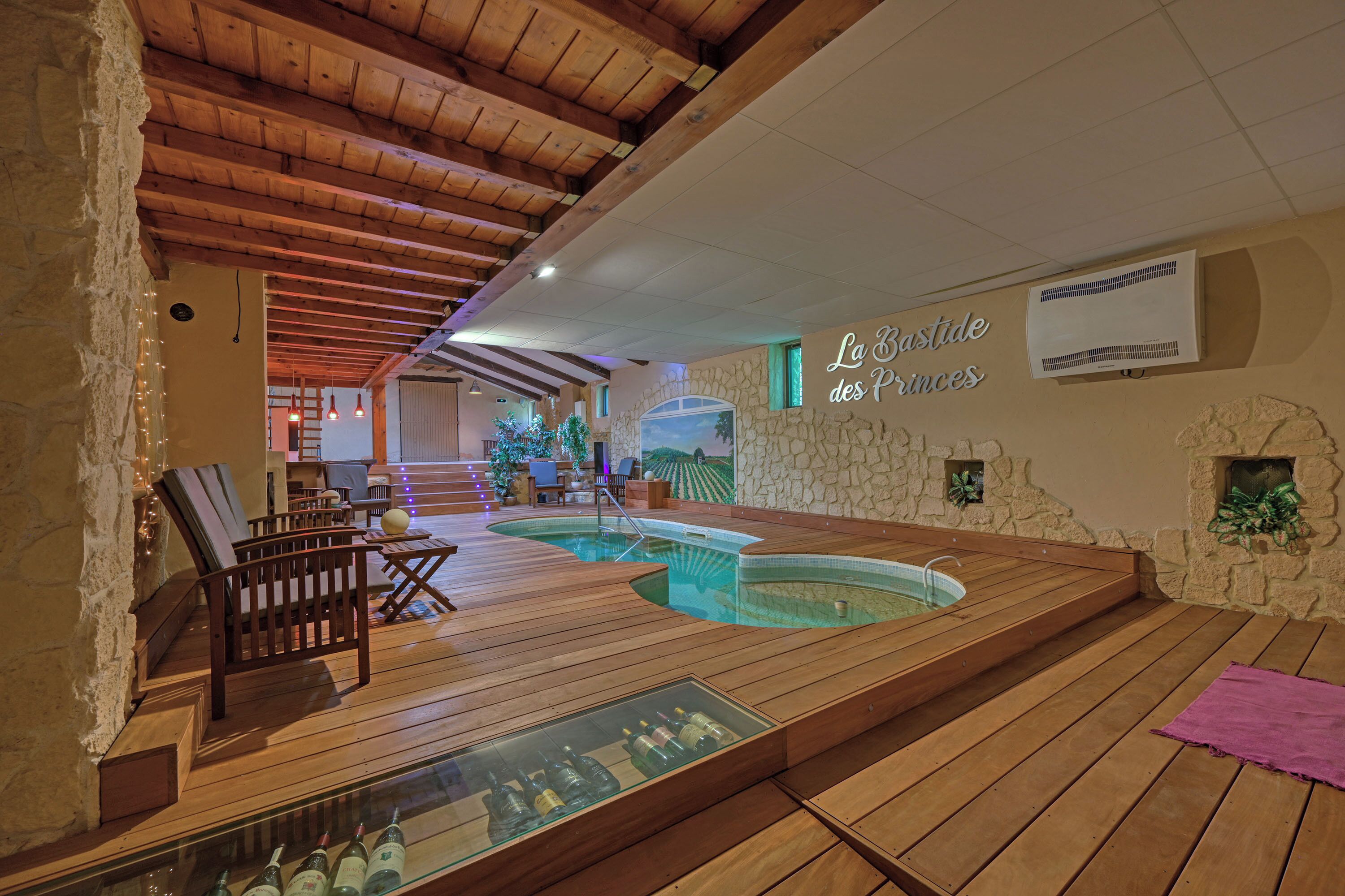 A spa area with wooden flooring, a hot tub, and a glass display of bottles.