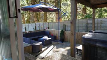 An outdoor patio area with a seating arrangement, a barbecue grill, and a wooden deck.