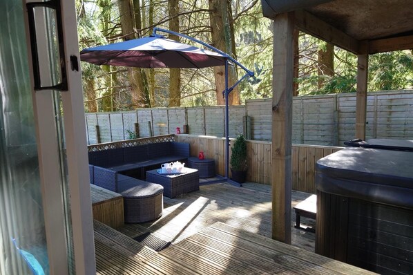 Un espacio al aire libre con patio, mobiliario para sentarse, una parrilla y una terraza de madera.