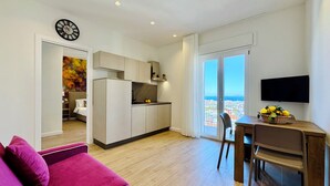 Un appartement moderne comprenant une cuisine, un coin repas et un salon avec un canapé rose.